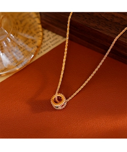 Detail van gouden ketting met driekleurige zirkoon hanger op vintage leer decor