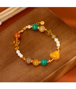 Détail macro du bracelet perlé multicolore avec breloque Bouddha dorée sur support
