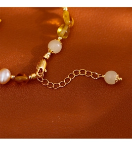 Vue détaillée d'un bracelet de perles avec fermoir mousqueton doré sur cuir marron