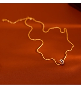 Detailopname van gouden cilinder hanger met gekleurde edelstenen op bruin leder