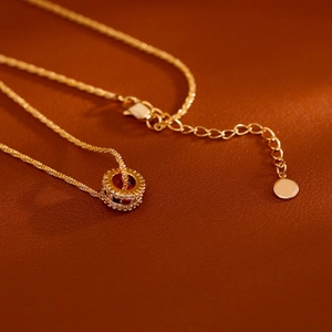 Elegante gouden ketting met ronde hanger met gekleurde edelstenen op donker lederen basis