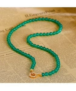Détail de perles de calcédoine verte avec un fermoir à ressort doré serti de zircon