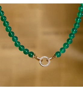 Détail de perles de calcédoine verte et d'un fermoir doré orné de pierres brillantes
