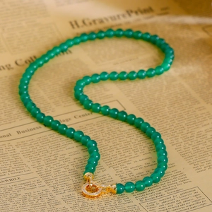 Collier en calcédoine verte avec fermoir doré serti de cristaux sur fond de papier rétro