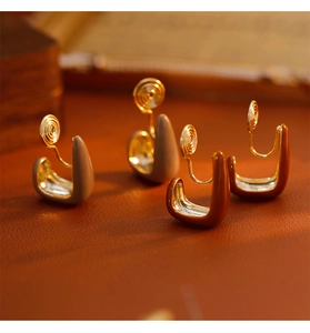 U-shaped clip-on earrings in Morandi tones on a vintage leather surface
