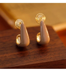 Macro shot of U-shaped mocha enamel clip-on earrings on a vintage wooden base