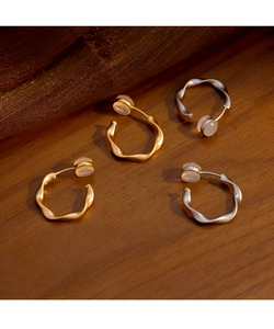 Détail de boucles d'oreilles torsadées dorées et argentées avec coussinets en silicone