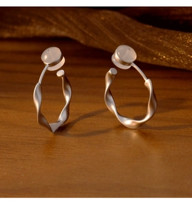 Gros plan de boucles d'oreilles torsadées argent mat avec coussinets en silicone