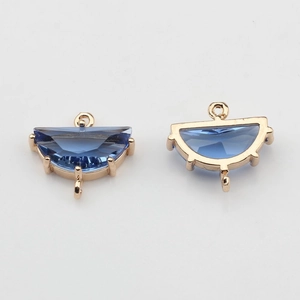 Detailed view of two gold-plated fan-shaped charms with dark blue crystal for DIY jewelry