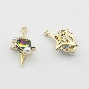 Detalle de colgante de estrella dorada con gema de corazón irisada y dos perlas