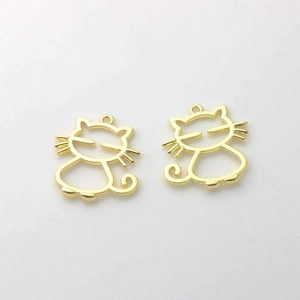 Gros plan de deux pendentifs chats dorés évidés pour la création de bijoux DIY créatifs