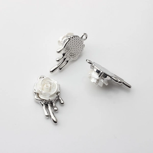 Detailed views of silver flower charms with white petals for DIY jewelry making
