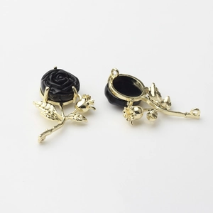 Macro detail of 3D black rose alloy charms with gold leaf base for DIY jewelry making