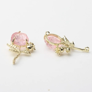Detailed view of two gold alloy rose flower charms with pink petals for DIY jewelry making