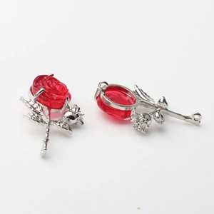Detailed view of silver rose pendants with translucent red petals for DIY jewelry making