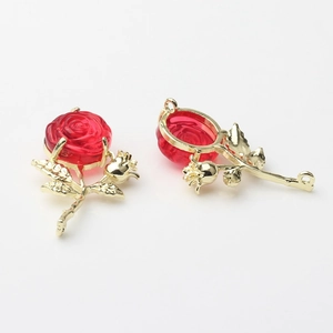 Detailed view of red resin rose pendants with gold metallic leaves and dual hanging rings