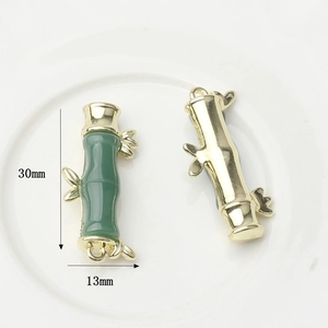 Macro shot of 30mm bamboo-shaped gold alloy pendants with green imitation jade inlay