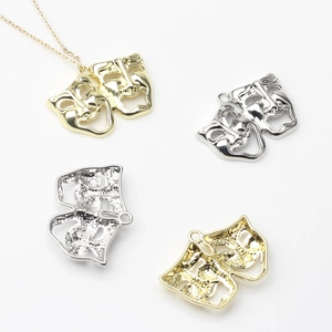 Golden and silver comedy tragedy mask pendants with chains on white background