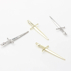 Close-up of gold and silver long sword pendants with decorative hilts for DIY jewelry