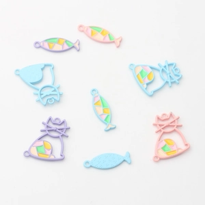 Pastelkleurige emaille kat- en visbedeltjes voor DIY-sieraden op een witte achtergrond