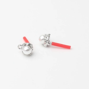 Detail view of pearl stud earring components with silver metal base and red safety caps