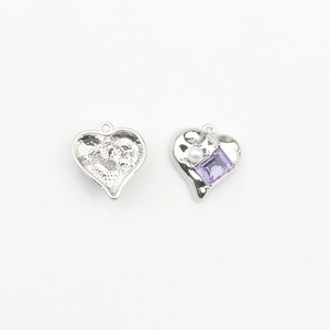 Detailed view of silver heart charms with purple crystal, pearl and textured back