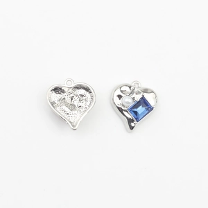 Macro detail of heart-shaped alloy pendants with blue zircon and pearl inlay details