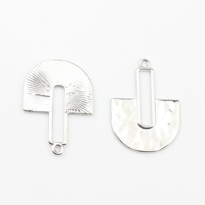 Detailed view of silver geometric fan pendants with hammered and radial metal textures