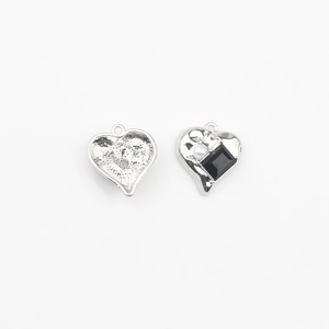 Detailed view of silver heart charms with black stone and white pearl inlay for DIY jewelry