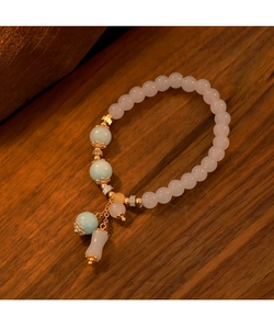 Detalle macro de una pulsera de piedras naturales con cuentas rosas y detalles dorados