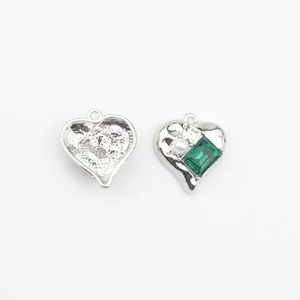 Detailed view of heart-shaped silver pendant with green emerald and white round pearl