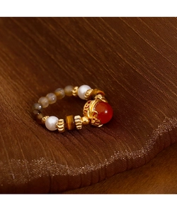 Macro detail of red agate and tiger eye stone beaded ring on brown silk background
