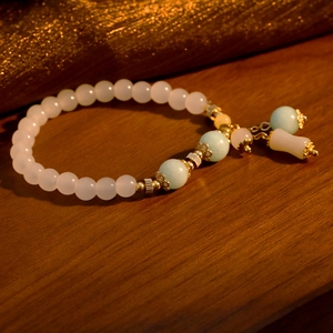 Elegante pulsera de cuentas de piedra natural con detalles azules y dorados sobre madera