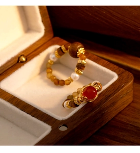 Macro detail of retro beaded rings with red agate and tiger eye stone in a wooden box