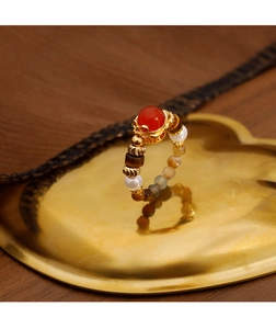 Detailed macro shot of vintage tiger eye and red agate beaded ring on a gold tray