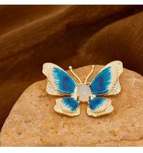 Macro detail of enamel butterfly brooch with blue gradient wings and crystal edging