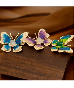 Detailed macro view of enamel butterfly brooches with gemstones on wooden stand