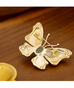Macro shot of gold butterfly brooch with translucent gemstone and detailed wing texture