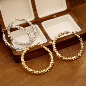 Boucles d'oreilles créoles dorées et argentées texturées sur une boîte à bijoux en velours