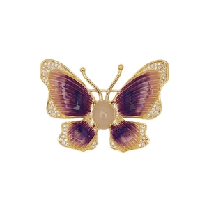 Golden butterfly brooch with purple enamel wings and gemstones on white background