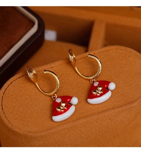 Dettaglio di orecchini a clip dorati a U con ciondoli a cappello di Babbo Natale