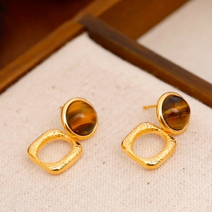 Pendientes vintage de oro con ojo de tigre y aros texturizados sobre tela color beige
