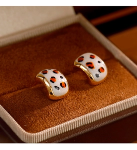 Vue macro de boucles d'oreilles émaillées léopard rétro français dans un écrin de velours