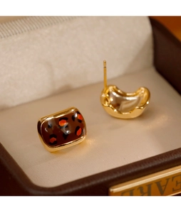 Détail macro de boucles d'oreilles carrées en émail léopard vintage dans un coffret luxe