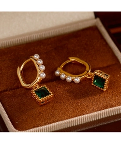 Close-up of vintage emerald square drop earrings with white pearls in a jewelry box