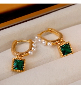Detail of vintage gold earrings with emerald green stone and white pearl accents
