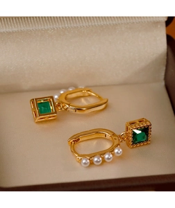 Detail of vintage gold earrings with square emerald stones and delicate white pearls
