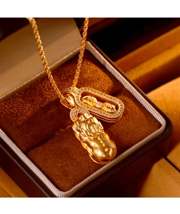 Macro shot of matte gold Pixiu and Vajra pendants with white gemstone accents