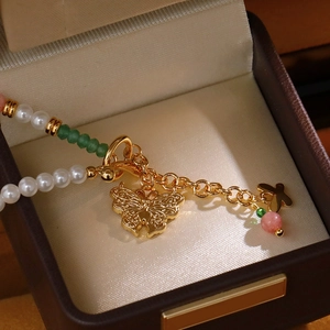 Elegantes Perlenarmband mit grünen Perlen und Schmetterlingsanhänger auf Schmuckdose