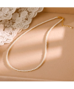 Detailed macro view of 2mm small round pearls with a gold adjustable clasp on velvet